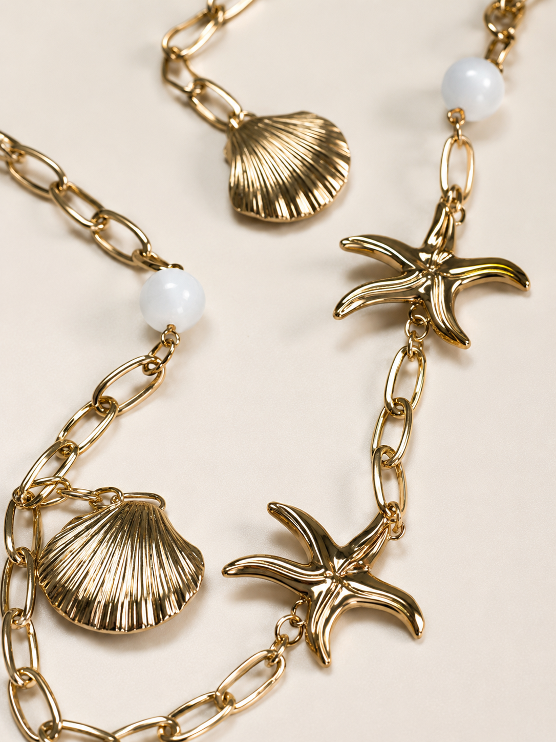 Collana lunga dorata con conchiglie, stelle marine e perle bianche