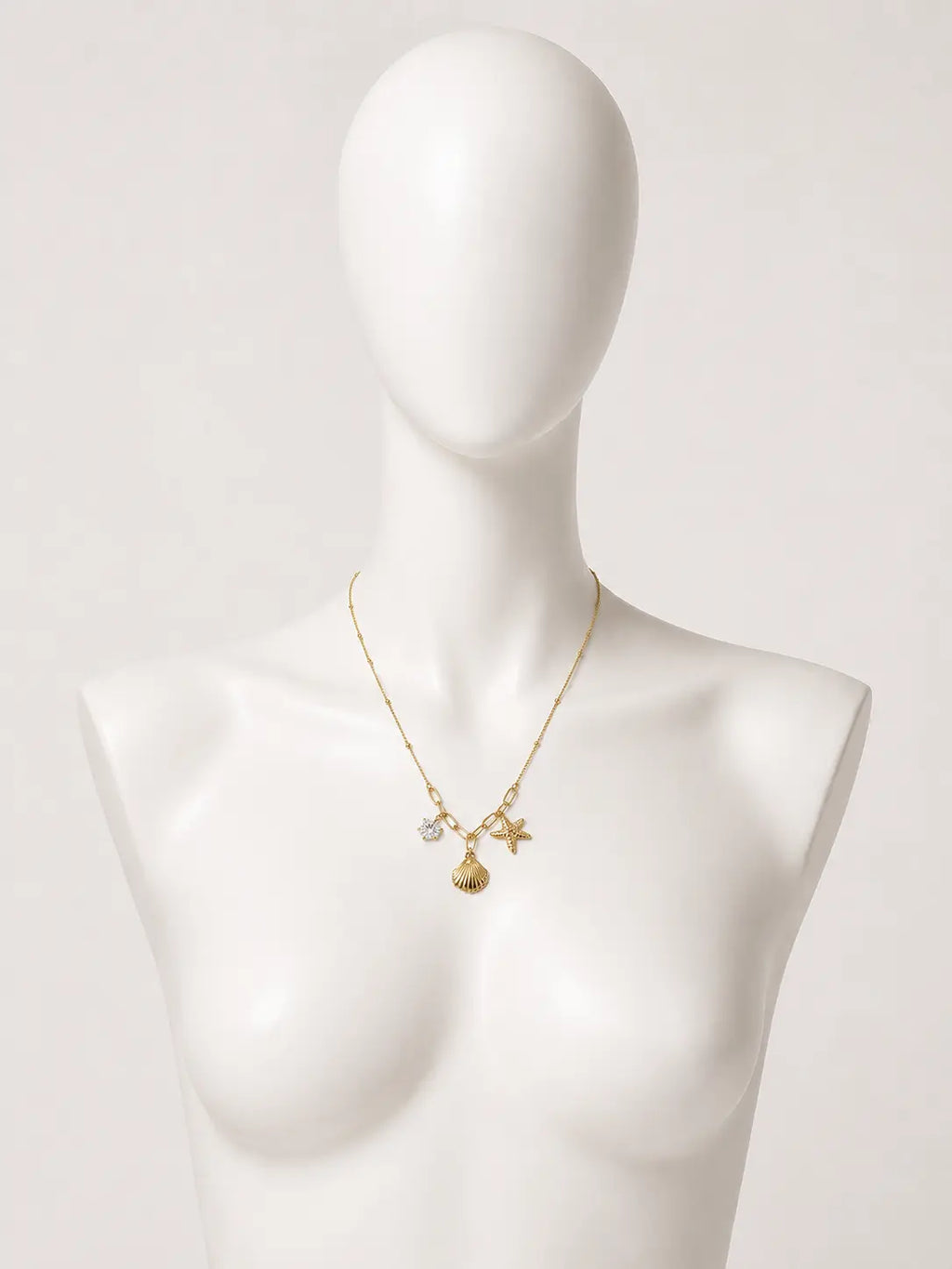 Collana dorata con conchiglia, stella marina e punto luce