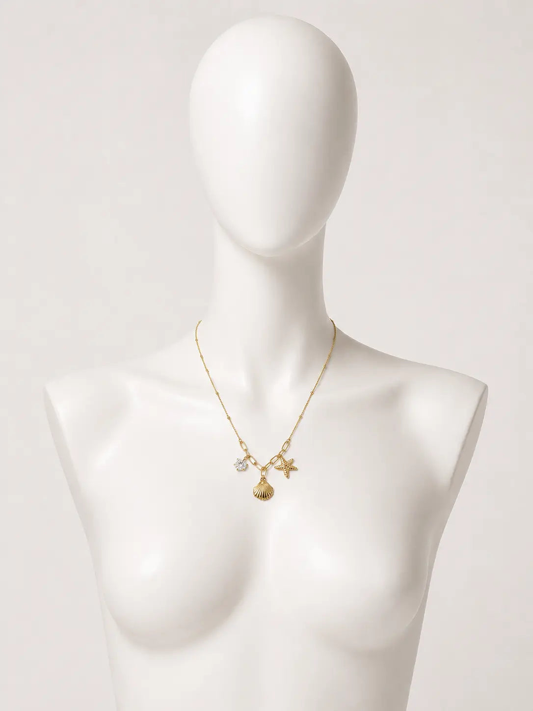 Collana dorata con conchiglia, stella marina e punto luce